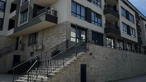 Un immeuble résidentiel à plusieurs étages, doté de balcons, d’un escalier et d’un rez-de-chaussée pavé.