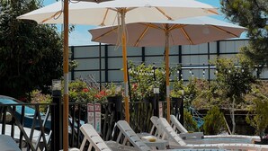 A poolside area with lounge chairs and umbrellas, a brick pathway, and a building in the background. - Casa Del Mar (Batumi)