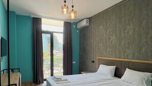 A hotel room with two beds, a desk, and a view of the outdoors. - Casa Del Mar (Batumi)