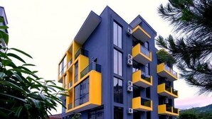 A modern multi-story building with balconies, a paved courtyard, and air conditioning units. - Casa Del Mar (Batumi)