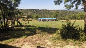 A rustic wooden playhouse with a slide and a picnic table in a grassy field. - DOUBLE TENTS FOR 4 PEOPLE IN THE HEART OF NATURE! Espace ERICA (Saint-Projet)