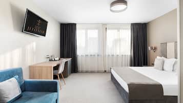 Habitación de hotel con cama, escritorio, silla y televisor mostrando el nombre del hotel.