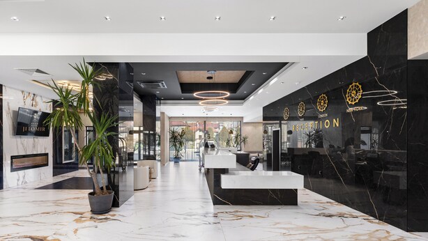 Un moderno vestíbulo de hotel con un mostrador de recepción, zona de estar y una gran planta en maceta.