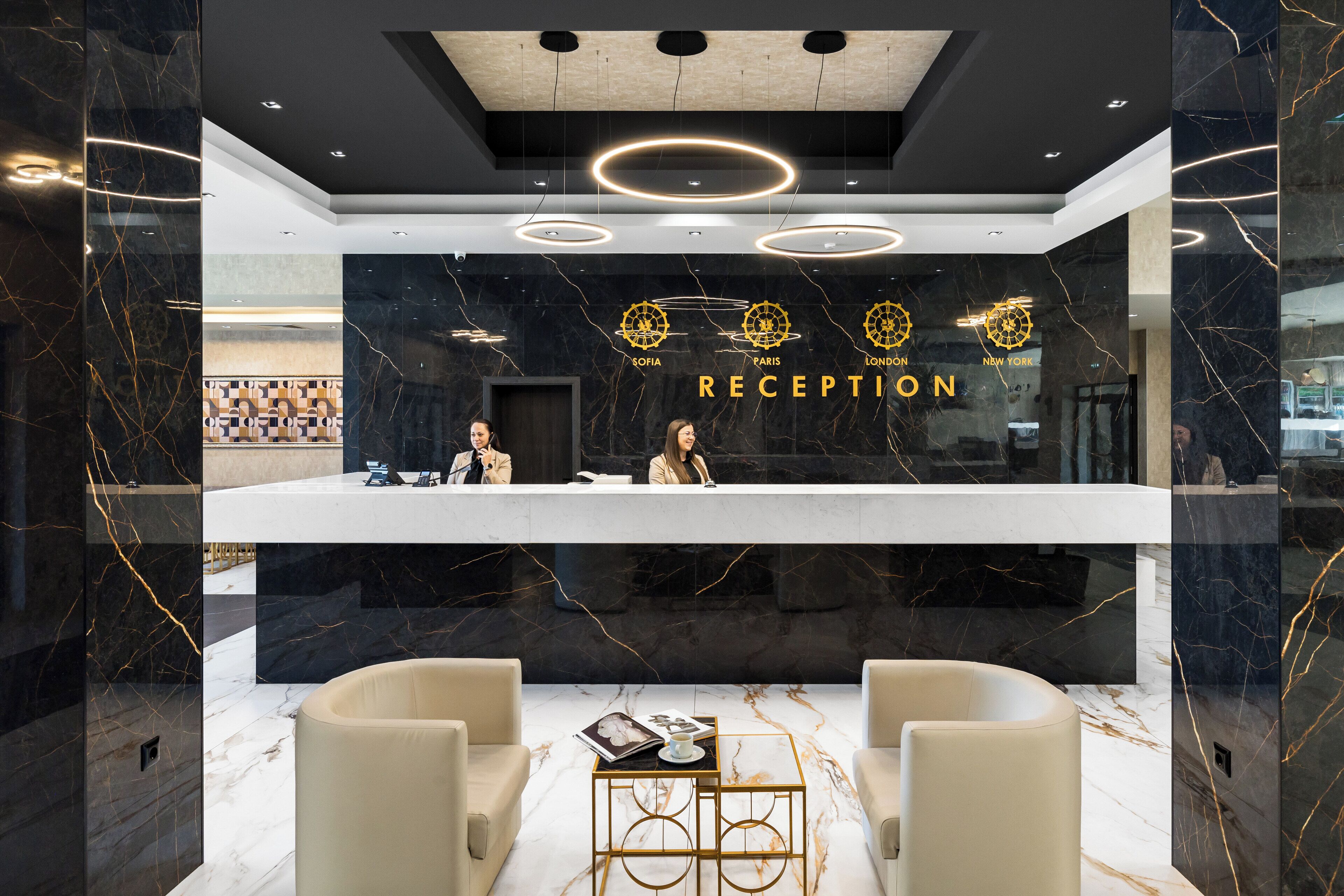 A modern reception area with a marble floor, a reception desk, and two seating areas.