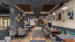 Un interior de restaurante moderno con suelo de madera, sillas tapizadas de color gris y mesas preparadas para comer.