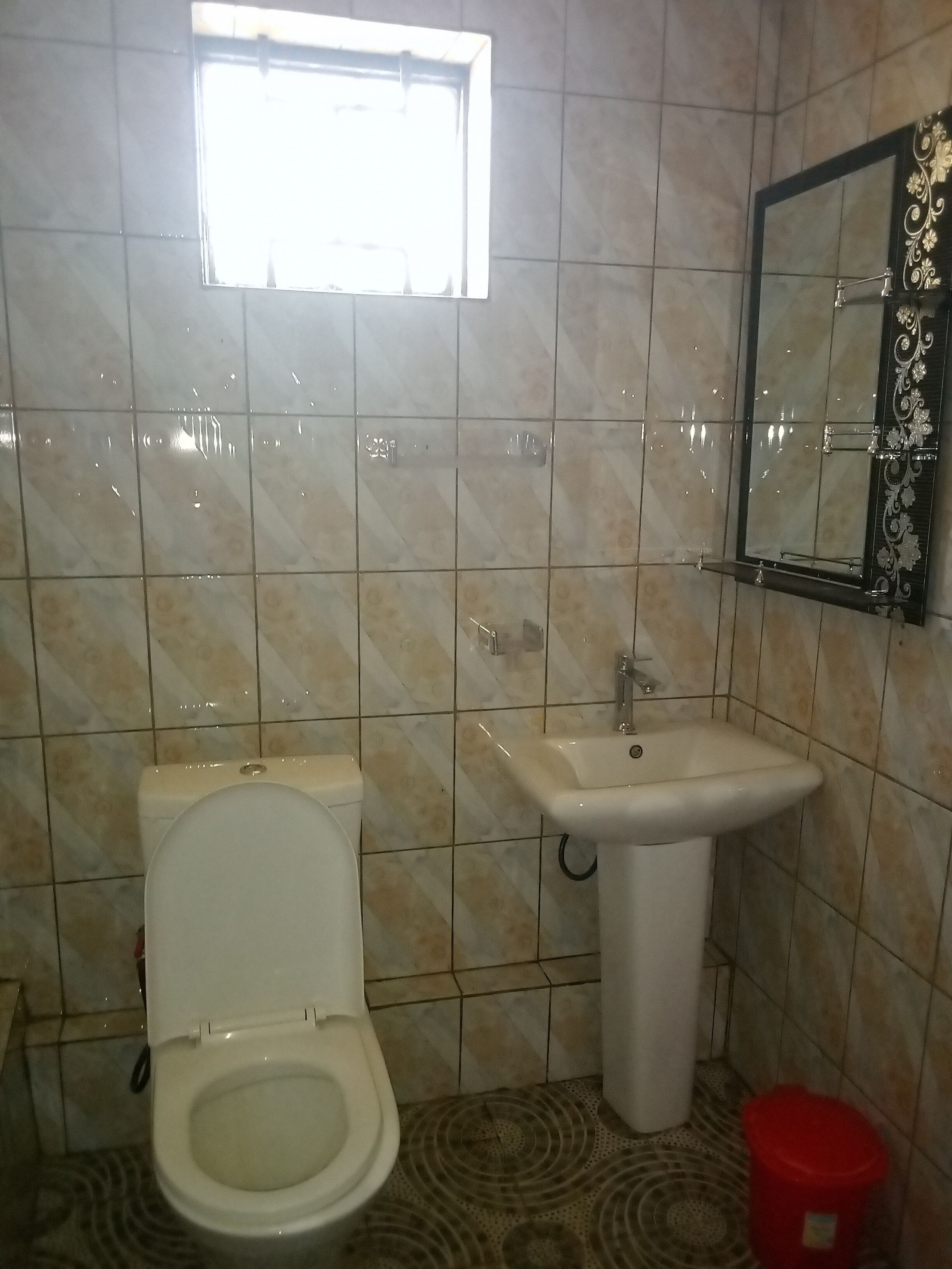 Une salle de bain équipée de toilettes, d’un lavabo et d’un miroir agrémenté d’éléments décoratifs.