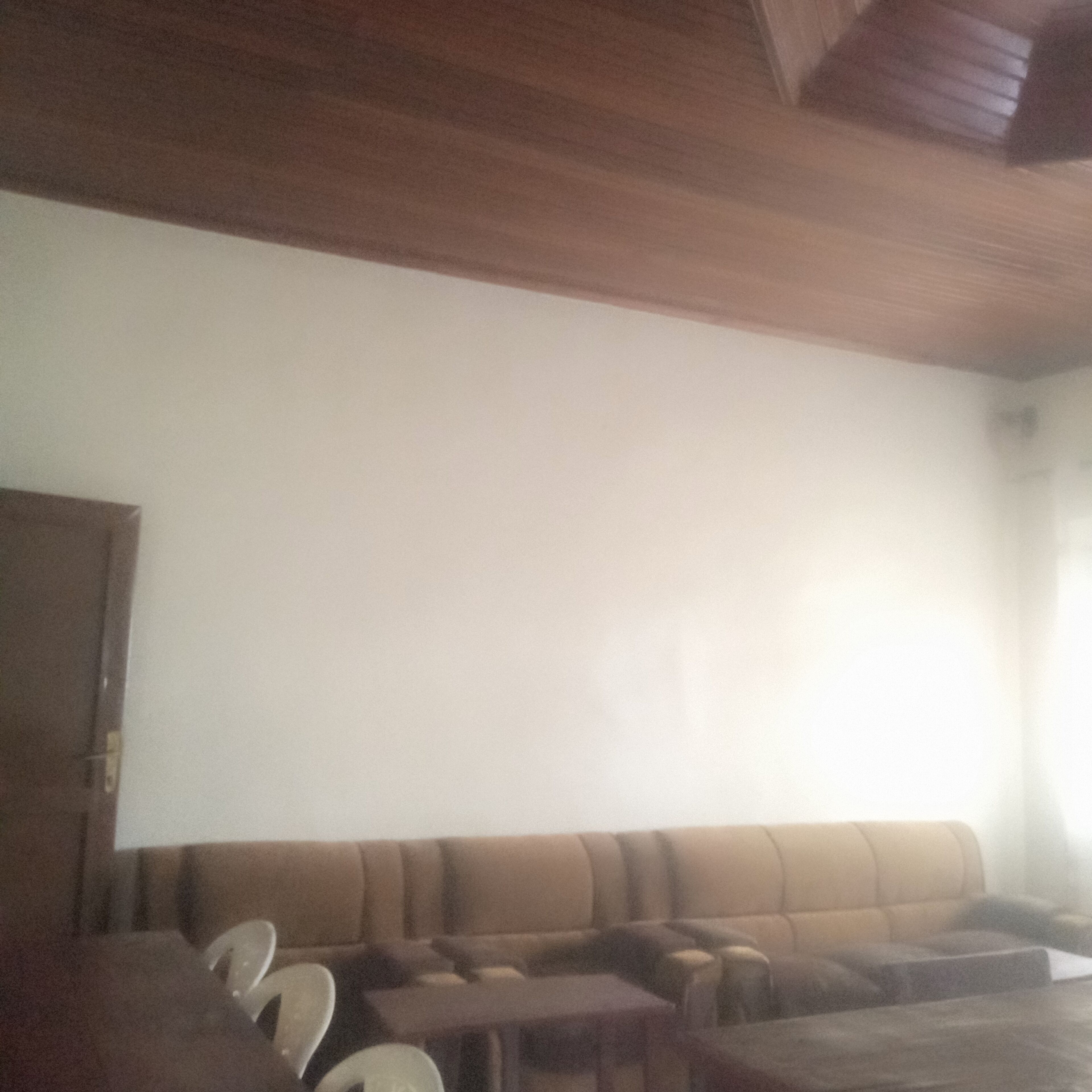 Una habitación con un sofá marrón, techo de madera y pared blanca.
