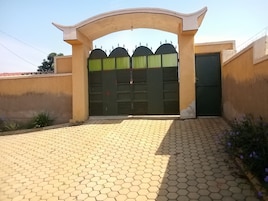 Uma entrada murada com portão verde e parede bege.