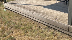 Ein überdachter Außenbereich mit Holzterrasse, Tisch und zwei Stühlen.
