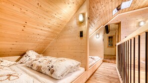 A wooden interior with a sloped ceiling, a bed with floral bedding, and a staircase with a railing. - Alp H tte Bregenzerwald (Schnepfau)