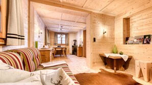 A cozy wooden interior with a sofa, a dining table, and a small kitchen area. - Alp H tte Bregenzerwald (Schnepfau)