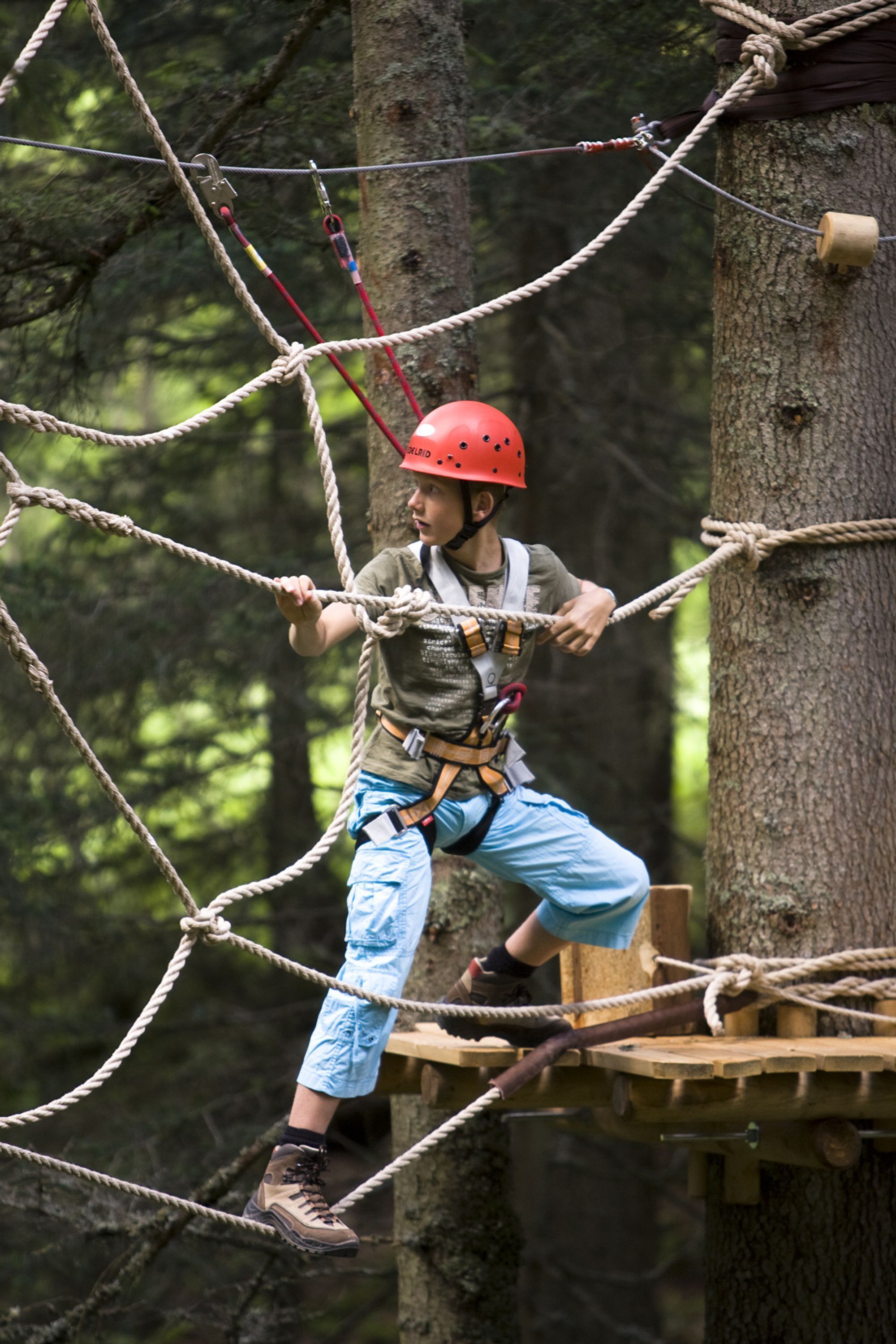 A person navigating a rope course in a forested area.