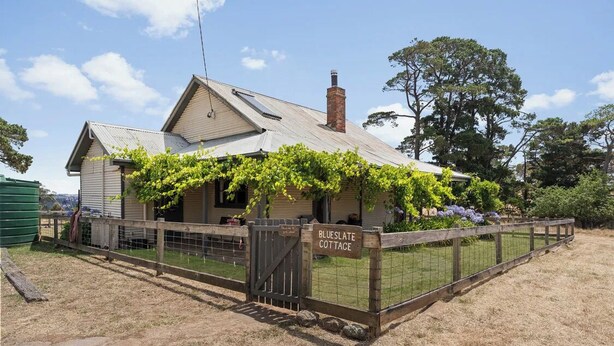 A house named 'Blueslate Cottage' with a fenced yard and a vine-covered porch.