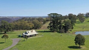 A rural property with a single house, a pond, and a hilly landscape.