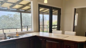 A kitchen with a gas stove, wooden cabinets, a large window, and pendant lights.