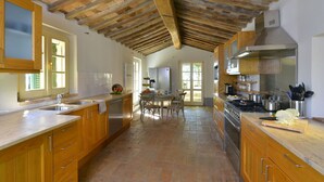 Una cocina amplia con armarios de madera, una isla grande y piso de baldosas de piedra.