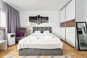 Ein modernes Schlafzimmer mit einem großen Bett, einem Nachttisch, einem Sessel, einer Lampe und einem Stadtbild an der Wand.