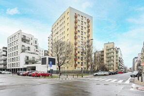 Ein mehrgeschossiges Wohngebäude mit Balkonen, einem Parkplatz und einer Fußgängerüberweg.