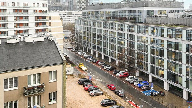Ein modernes Gebäude in der Stadt mit Parkplatz und Straßenansicht.