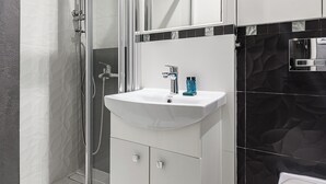 Ein modernes Badezimmer mit einer Duschkabine, einem weißen Waschbecken und einer Toilette.