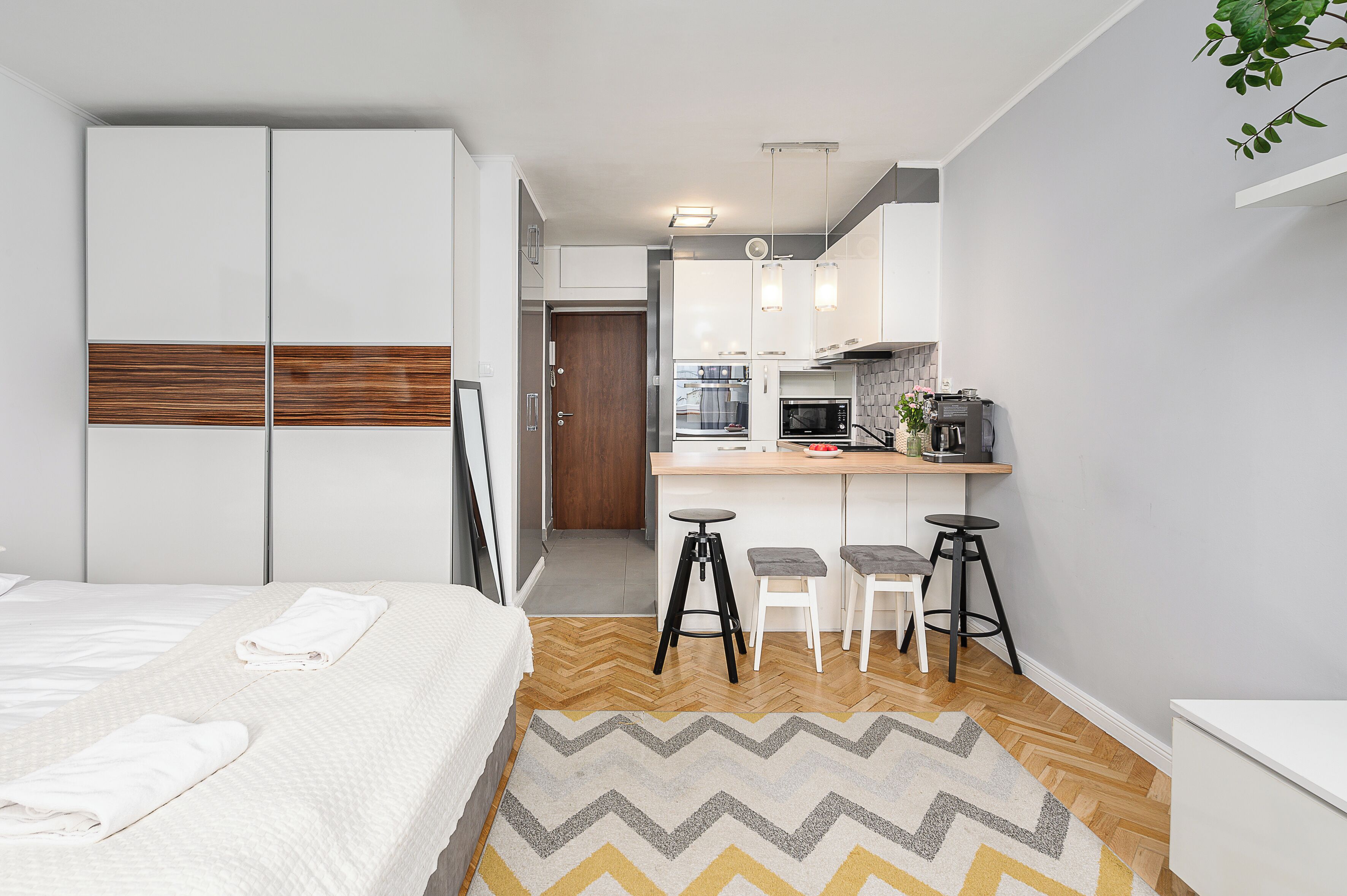 Een moderne hotelkamer met een bed, een bureau en een kitchenette.