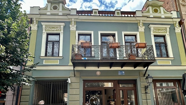 A building with a traditional architectural style, featuring a central entrance with a glass door and a balcony with potted plants. - Nova Charm Aparthotel in Old Tbilisi (Tbilisi)