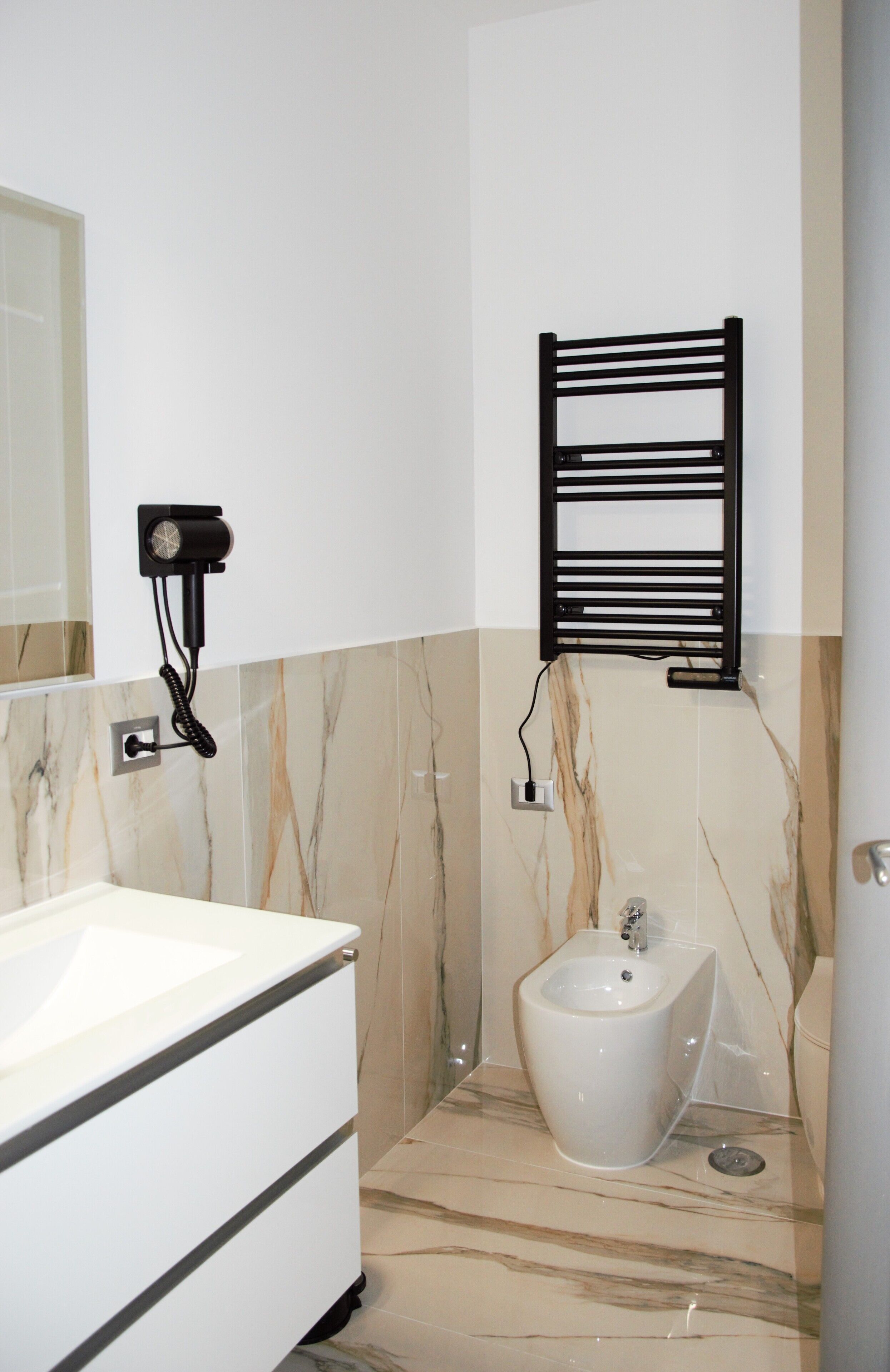 Ein modernes Badezimmer mit einem weißen Waschbecken, einem Bidet und einem Handtuchhalter.