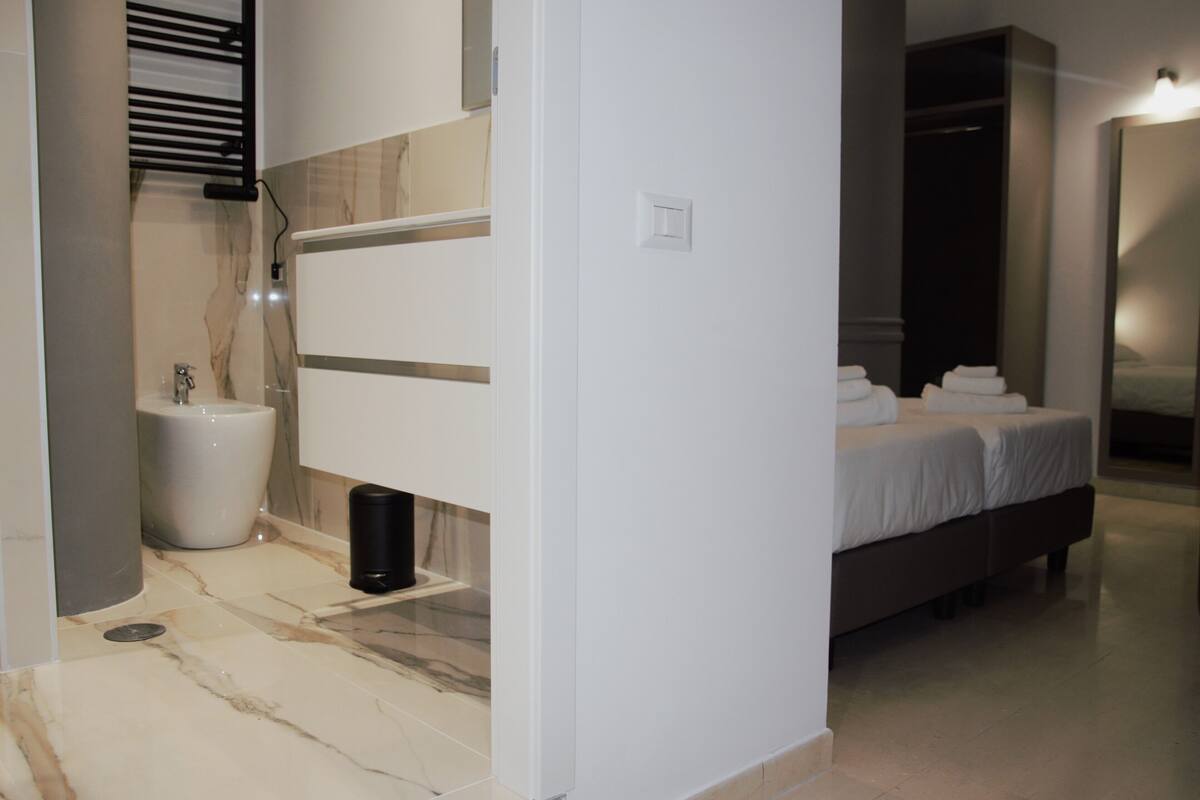A modern bathroom with a toilet, bidet, and a towel rack.