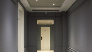 En gang med mørke vægge, lyst gulv og indbyggede loftslamper.