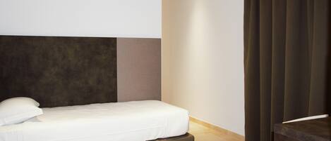 Ein modernes Hotelzimmer mit einem großen Bett, einem dunklen Kopfteil und Holzboden.