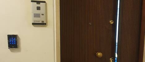 Una puerta de madera cerrada con un teclado de combinación numérica y un sistema de intercomunicador instalado en la pared.