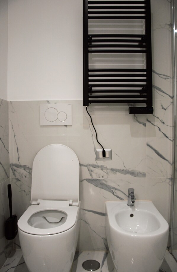 A modern bathroom with a toilet, bidet, and a towel rack.