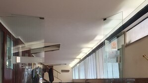 En rummelig lobby med marmortrin, der fører op til en trappe, en glas elevator og et skilt, der angiver et område, hvor rygning ikke er tilladt.