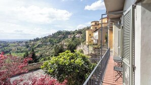 A balcony with a view of a hillside town, a railing, and a table with chairs. - The Donizettino (Bergamo)