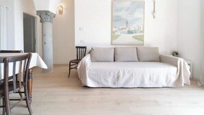 A room with a bed, a dining table with chairs, a chair, and a framed picture on the wall. - The Donizettino (Bergamo)