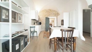 A dining area with a stone arch, a white table, and wooden chairs. - The Donizettino (Bergamo)