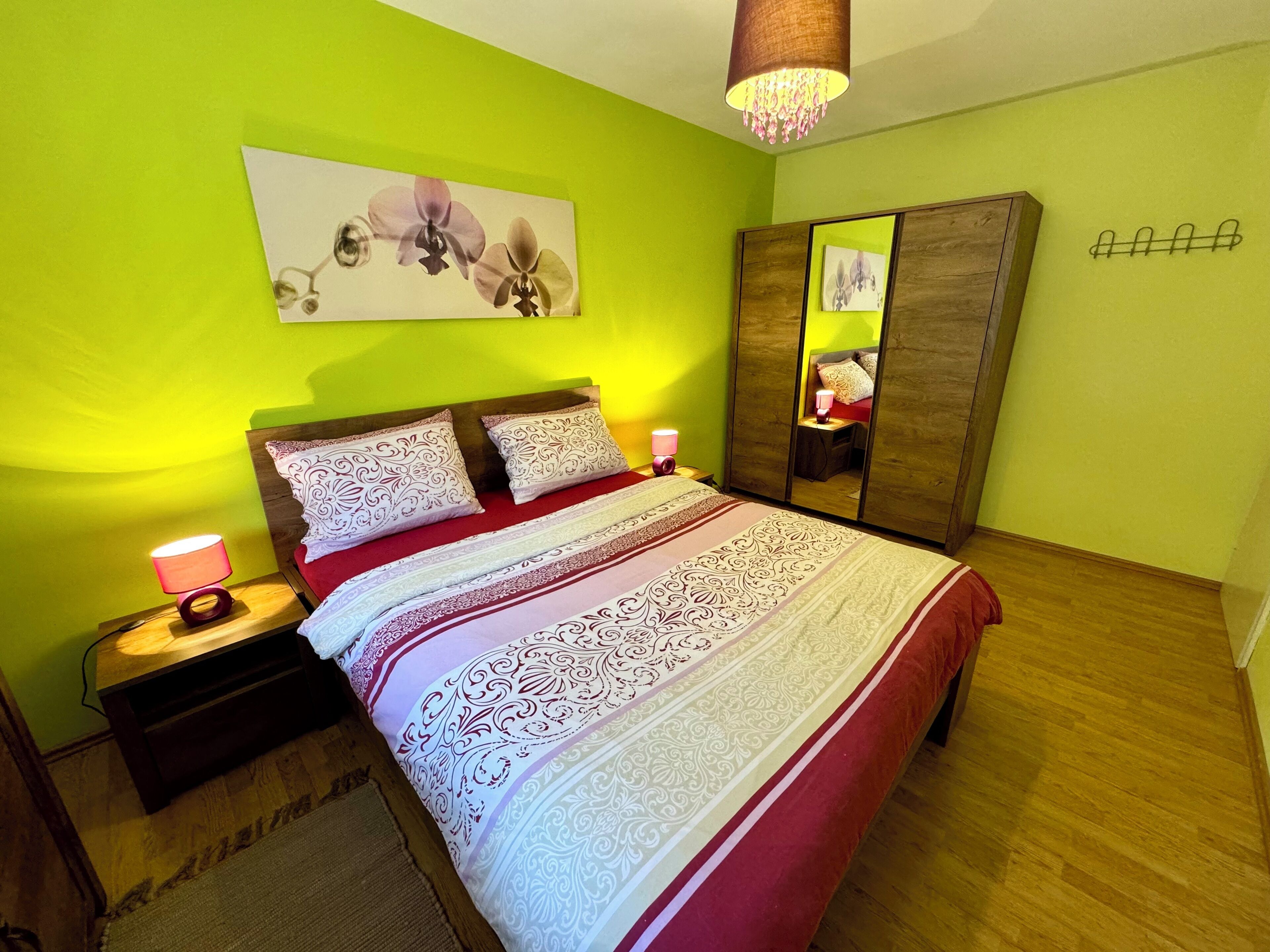 A bedroom with a bed, nightstands, a mirror, and a green wall.