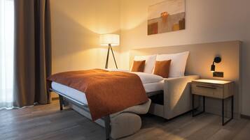 A modern hotel room with a bed, bedside table, lamp, and artwork on the wall.
