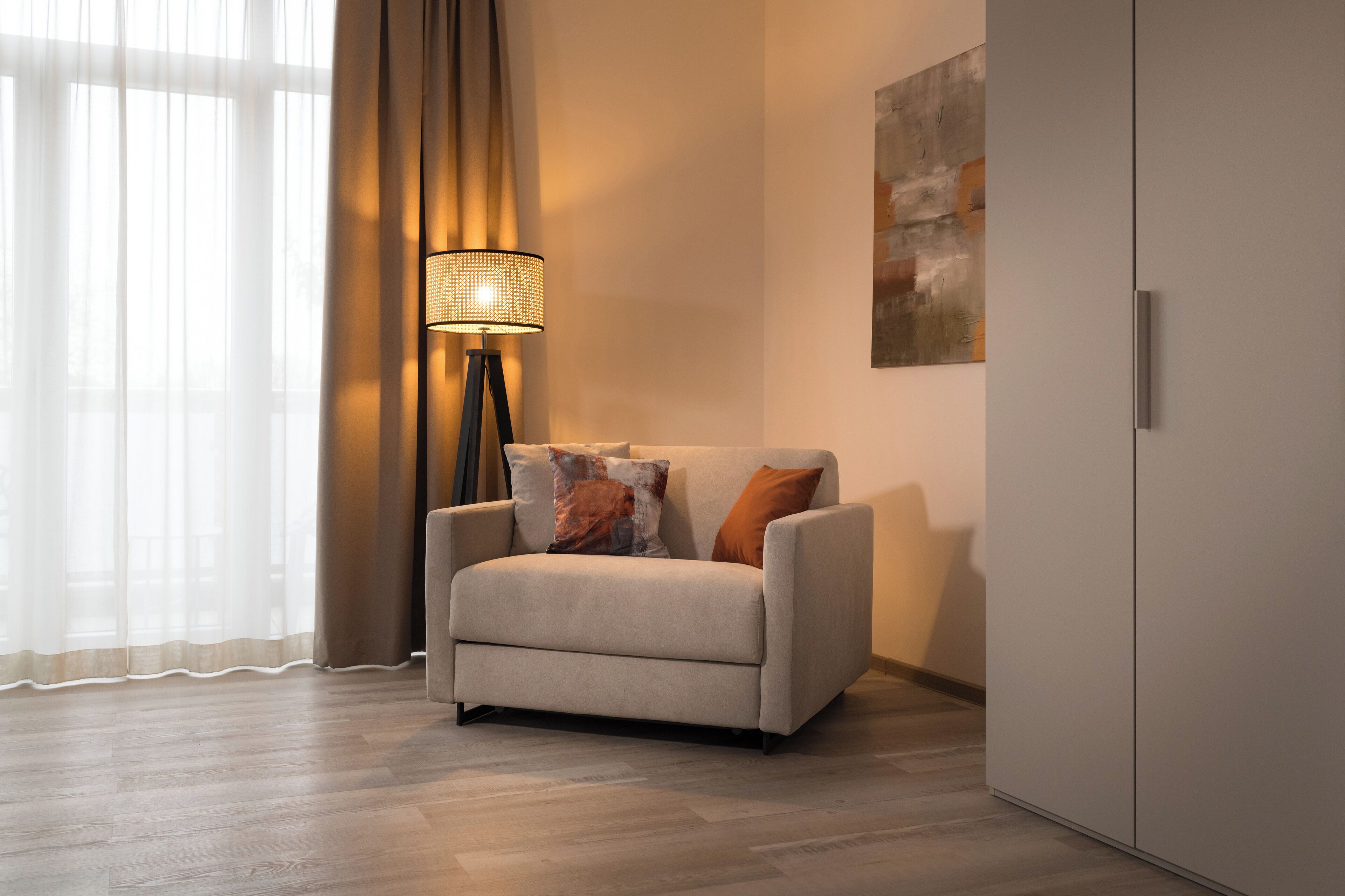 A modern living room with a sofa, a floor lamp, and a painting on the wall.