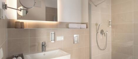 Un baño moderno con lavamanos, espejo, toallero y ducha.