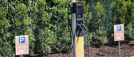 Un espace de stationnement équipé de bornes de recharge pour véhicules électriques et d’un panneau indiquant qu’il est réservé aux personnes accompagnées d’un enfant en bas âge (« pour les personnes avec enfants en bas âge uniquement »).