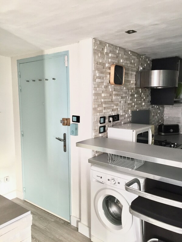 A compact kitchen with a washing machine, a microwave, and a built-in oven. - Bright 45m2 walk-through apartment (Aix-en-Provence)