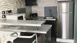 A modern kitchen with a built-in washer and dryer, stainless steel appliances, and a brick-patterned backsplash.