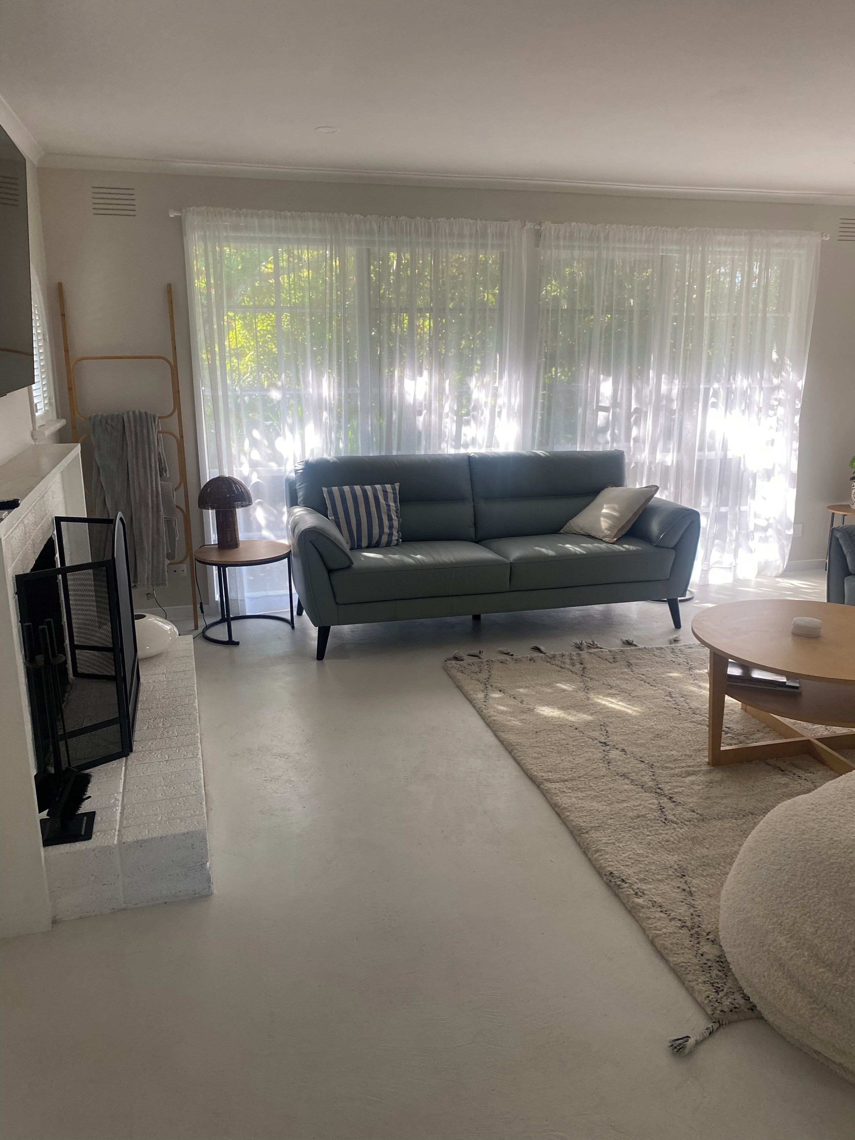 A living room with a grey sofa, a small round table, a white rug, and a fireplace.