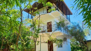 A multi-story building with a balcony, surrounded by trees and greenery. - Wanamal Lake Front Yala (Tissamaharama)