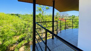 A covered outdoor area with a metal railing, a tiled floor, and a view of a green landscape. - Wanamal Lake Front Yala (Tissamaharama)
