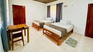 A hotel room with two beds, a wooden table, and a chair. - Wanamal Lake Front Yala (Tissamaharama)