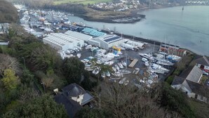 An aerial view of a marina with boats docked, a large industrial building, and a bridge in the background. - Marina House Annex - 1 Bedroom - Neyland (Milford Haven)