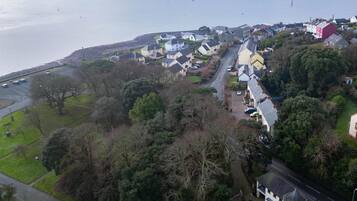 An aerial view of a coastal residential area with houses, a road, and a body of water.