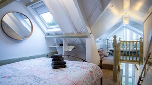 A bedroom with a bed, a mirror, a skylight, a staircase, and a view of the outside. - Stable Cottage - 1 Bedroom Cottage - Penally (Tenby)